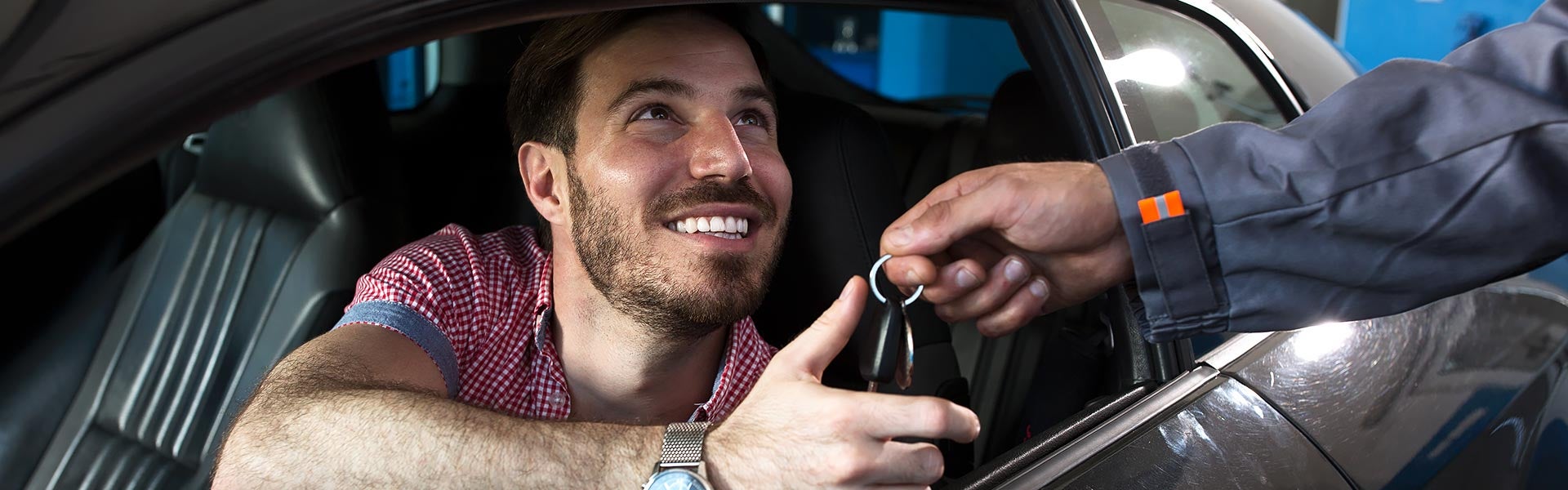 Keys being handed to a man sitting in a car